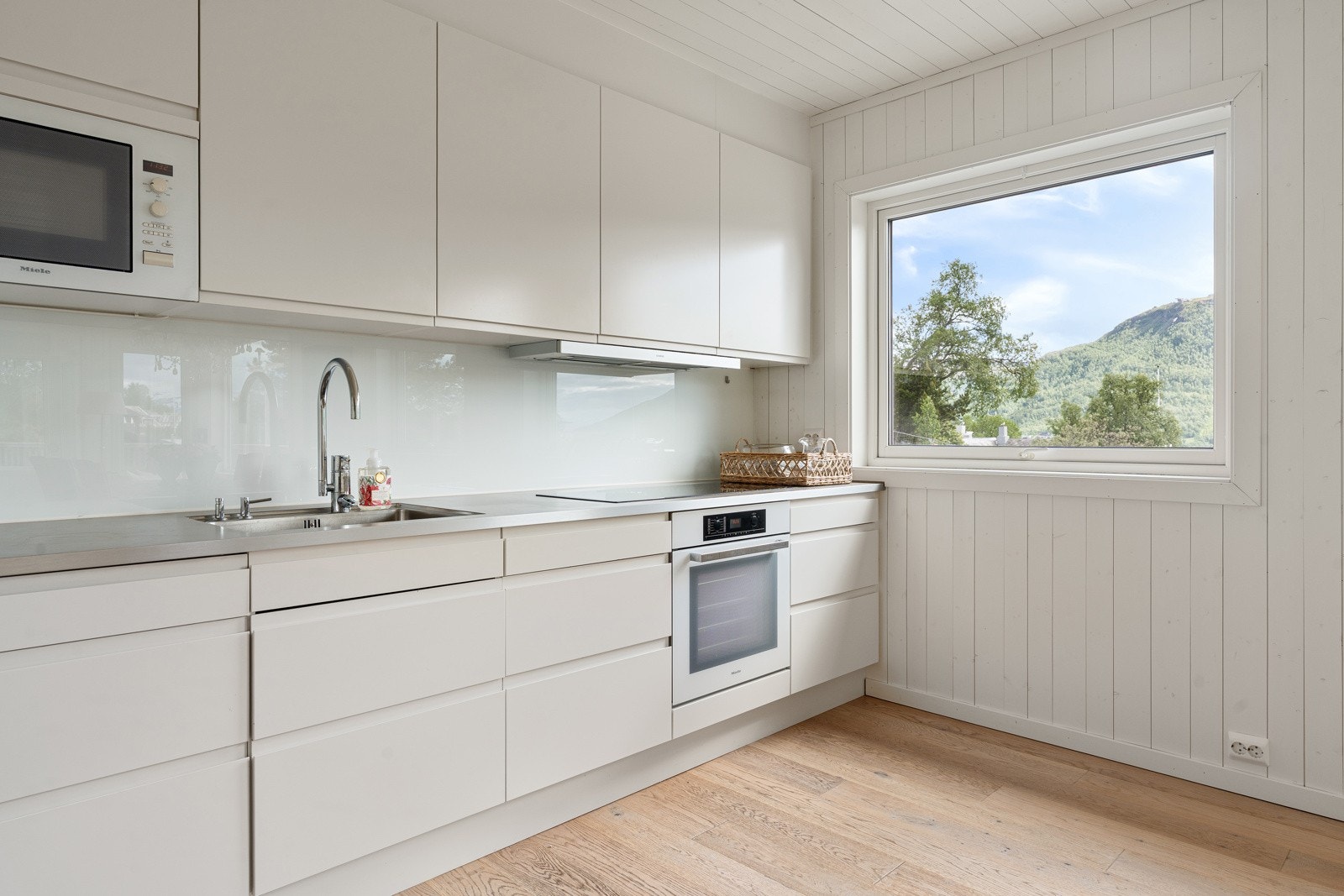 Kjøkkenet er tidløst med lys innredning. Det er kjøl/fryseskap, oppvaskmaskin, platetopp, micro og stekeovn.
