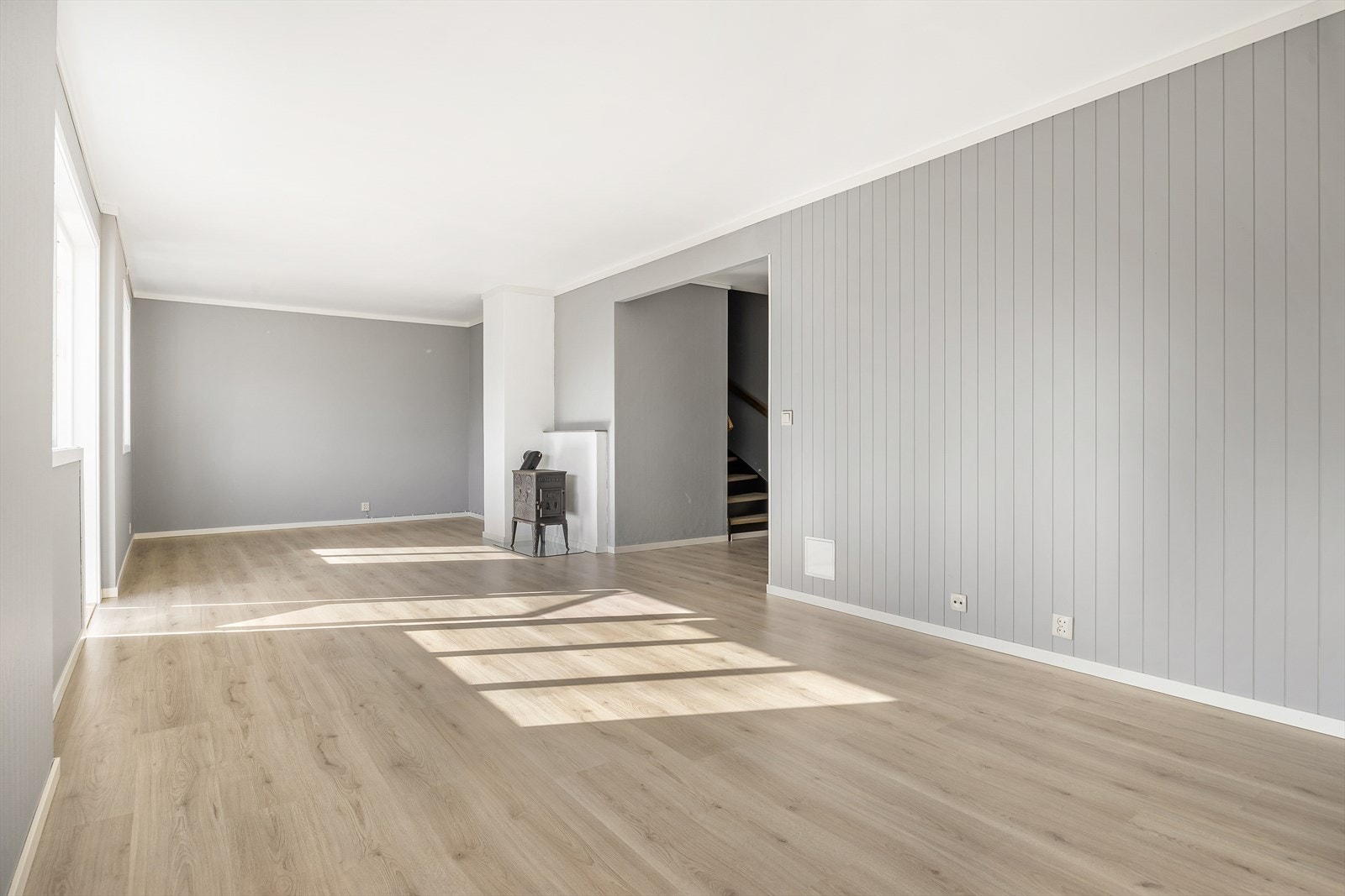 Rommet har mye lysinnslipp samt overflater med laminatgulv, gråmalte panelvegger og hvitmalt tak med listverk og karmer. Galleribilde