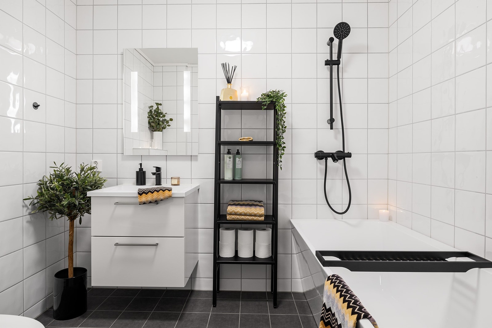 Flott flislagt bad i hovedetasjen med badekar med vegghengt dusjarmatur. Innredning med skuffer og speil med sidelys over servant. Vegghengt toalett Galleribilde