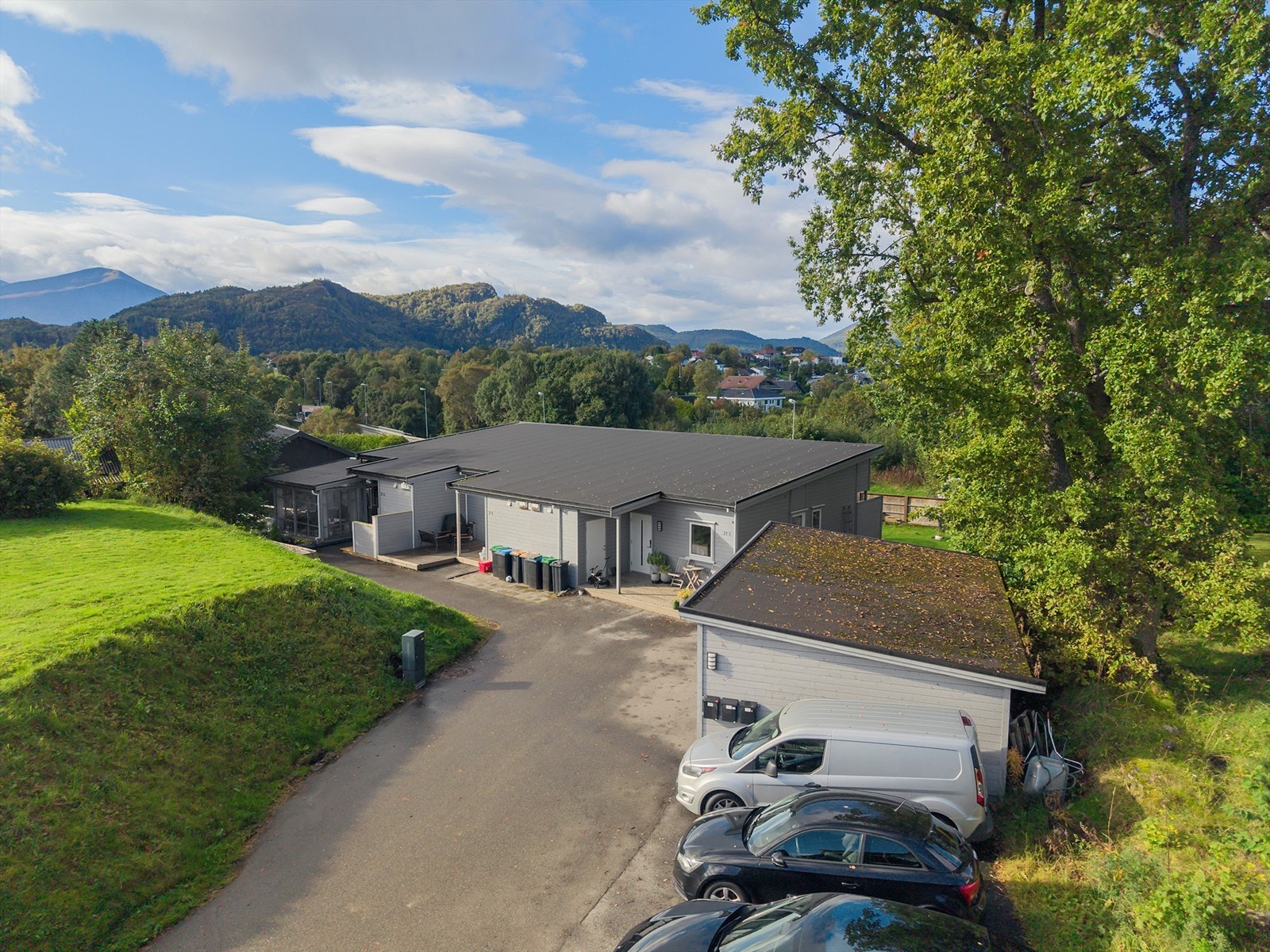 Dronebilde av fasade og felles carport og parkeringsplasser Galleribilde