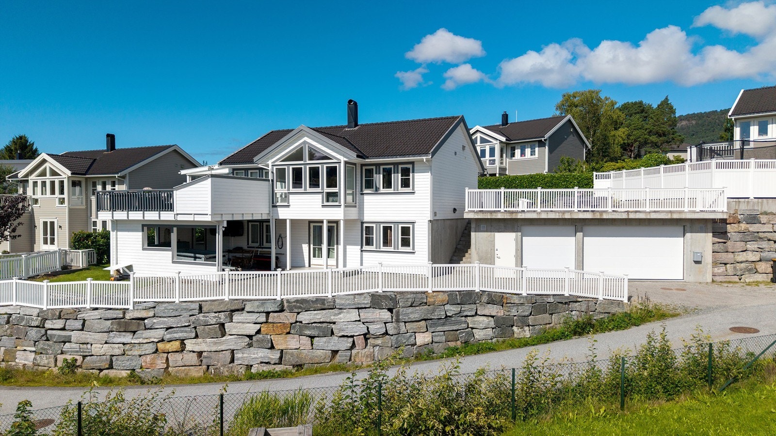 Eiendommen er rammet inn av en forseggjort forstøtningsmur i naturstein og hvitt gjerde. Galleribilde