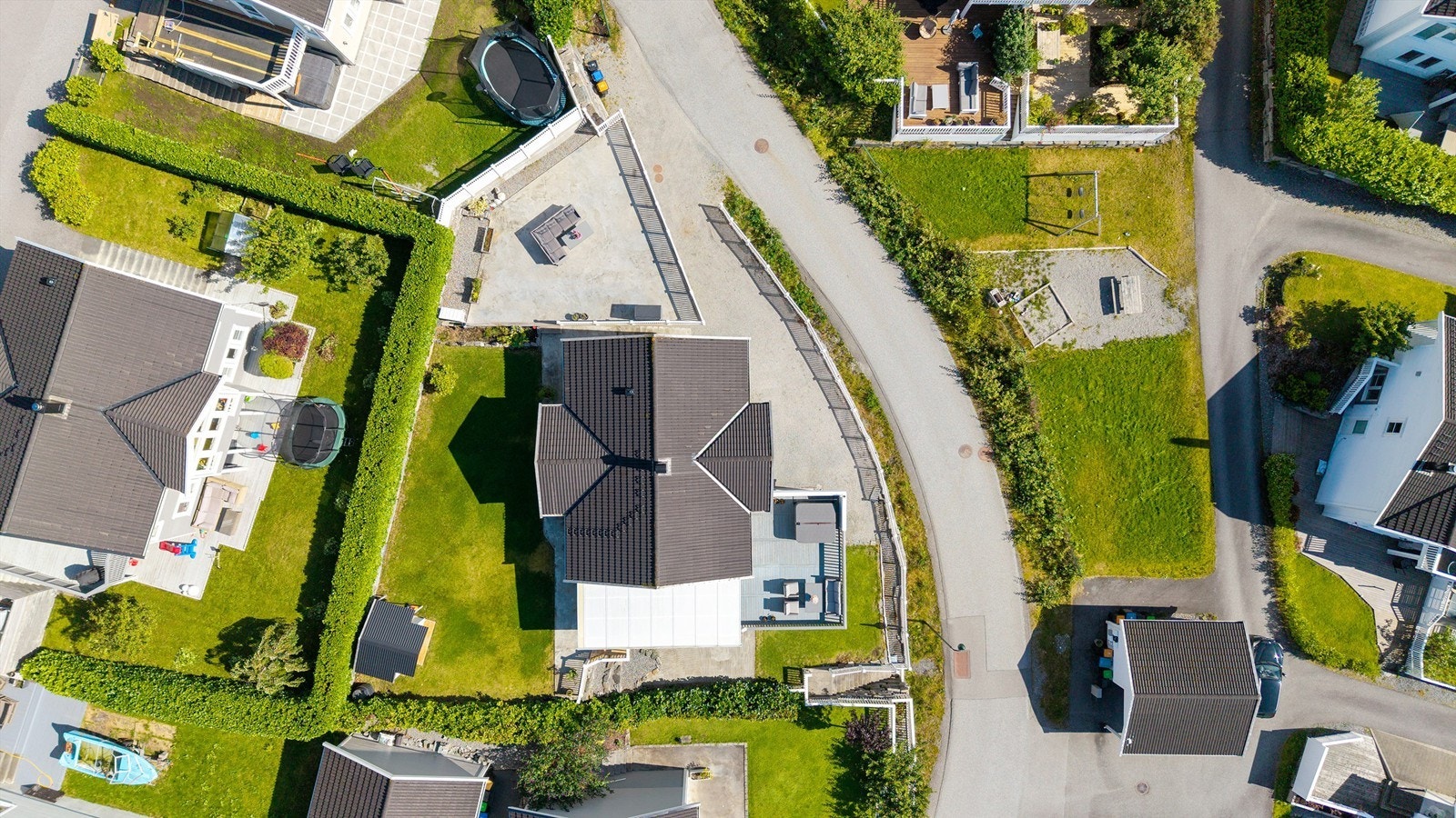 Tomten er opparbeidet i to nivåer med plenarealer, terrasser og gode parkeringsforhold. Galleribilde