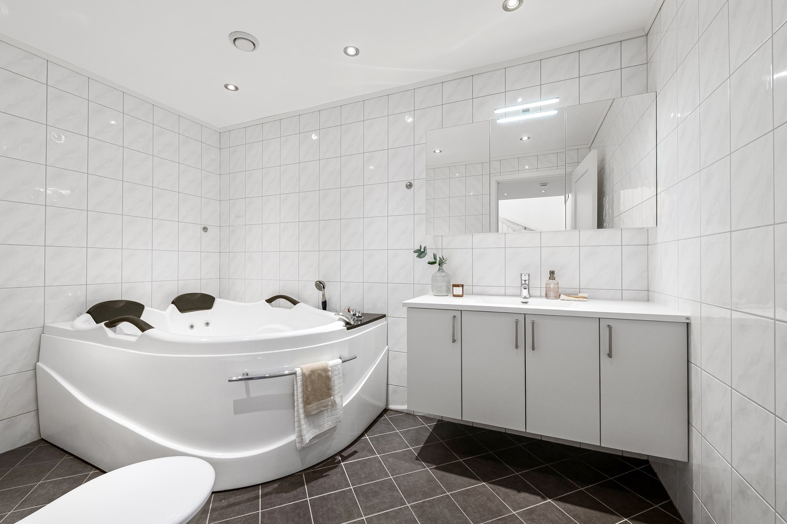 Flislagt bad i underetasjen med gulvvarme, med downlights og hjørnebadekar. Galleribilde