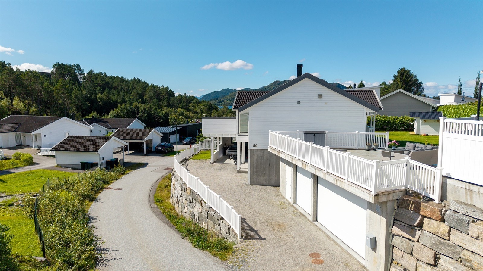Eiendommen ligger i rolige omgivelser med romslig gruset gårdsplass foran garasje og carport. Galleribilde