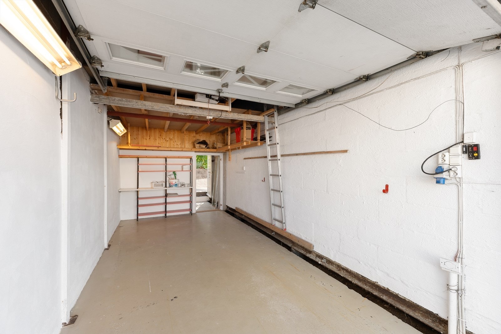Innvendig garasje med praktisk arbeidsbenk i bakkant og smarte hyller som gir gode oppbevaringsmuligheter. Galleribilde