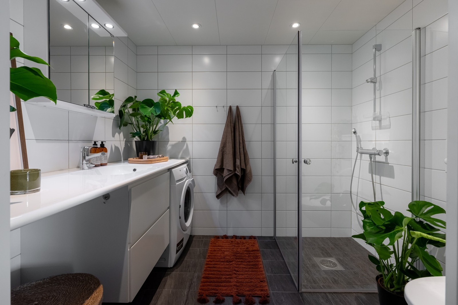 Lyst, flislagt baderom med varme i gulv og downlights i himling. Det er opplegg for vaskemaskin og plass til tørketrommel under benk. Galleribilde