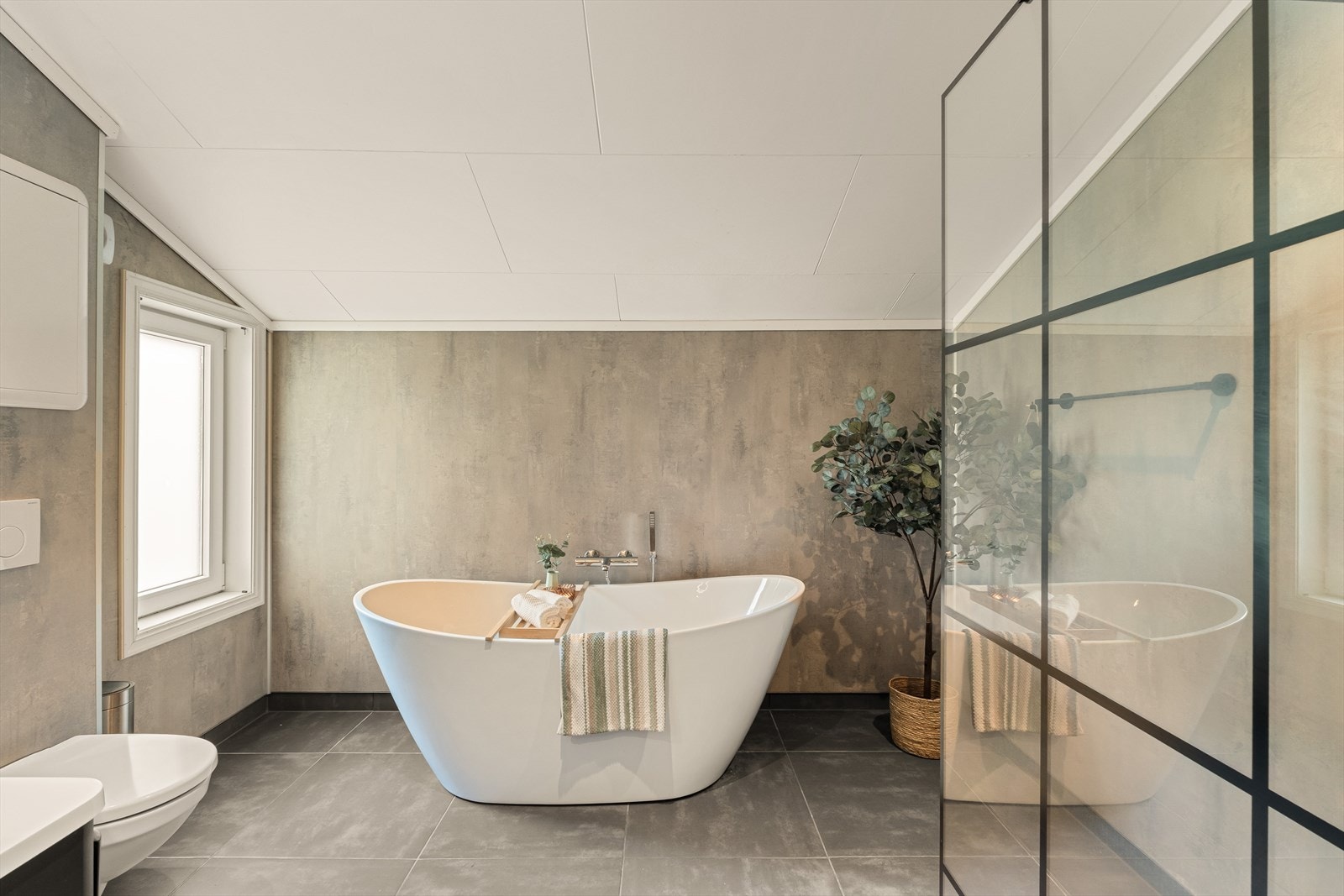 Badet har servant, veggmontert toalett, badekar og dusjhjørnet. Gulvet er flislagt og har elektriske varmekabler. Galleribilde
