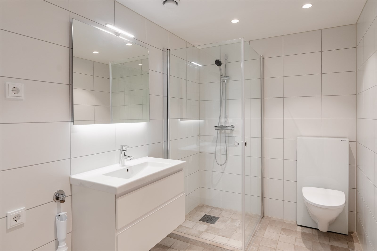 Greige gulvfliser og lyse veggfliser gir badet et tidløst uttrykk. Galleribilde