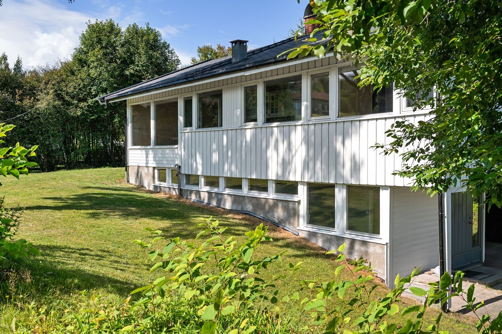Tomten er opparbeidet med plenarealer og diverse beplantninger. Galleribilde