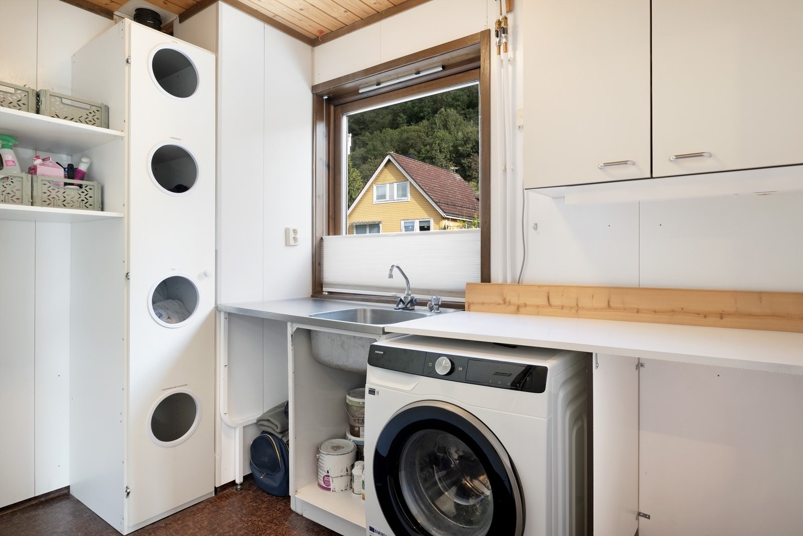 Praktisk vaskerom med utslagsvask, opplegg for vaskemaskin og benkeflate. Galleribilde