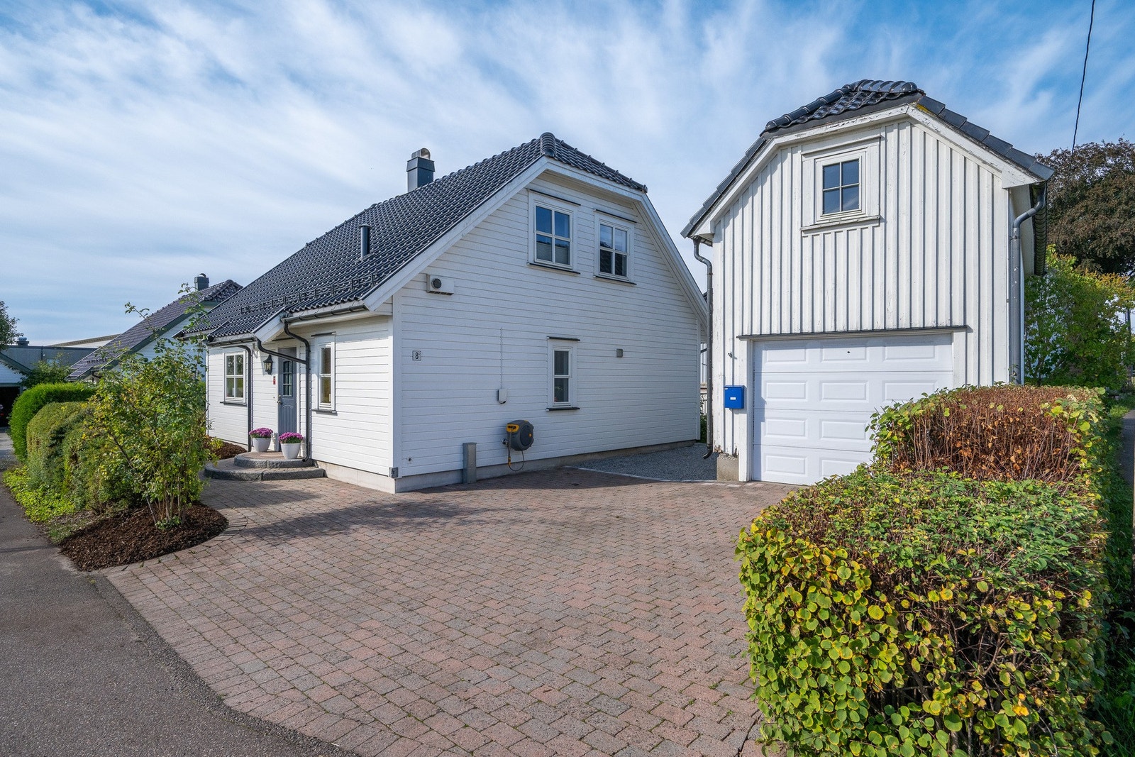 Eiendommen har en romslig, steinlagt gårdsplass med gode parkeringsmuligheter og frittstående garasje. Galleribilde