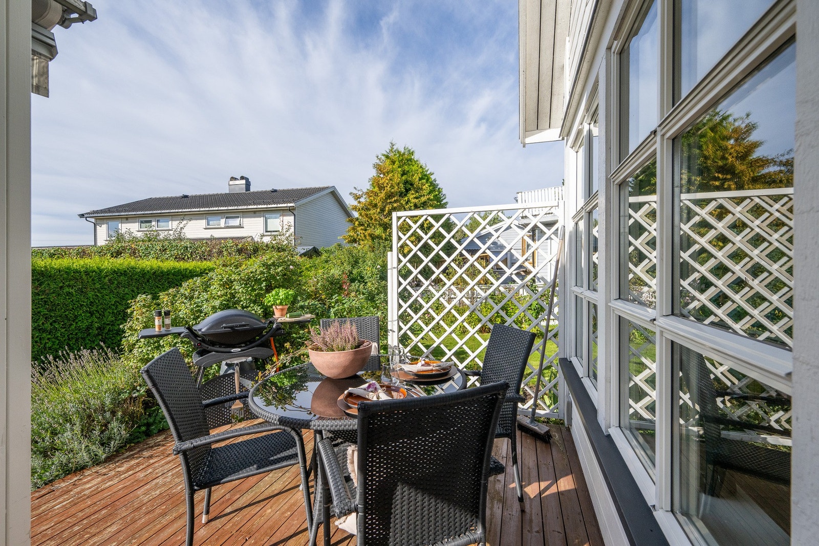 En koselig spiseplass utendørs gir fine muligheter for å nyte måltidene i frisk luft, omgitt av grønne hekker og blomstrende planter. Galleribilde
