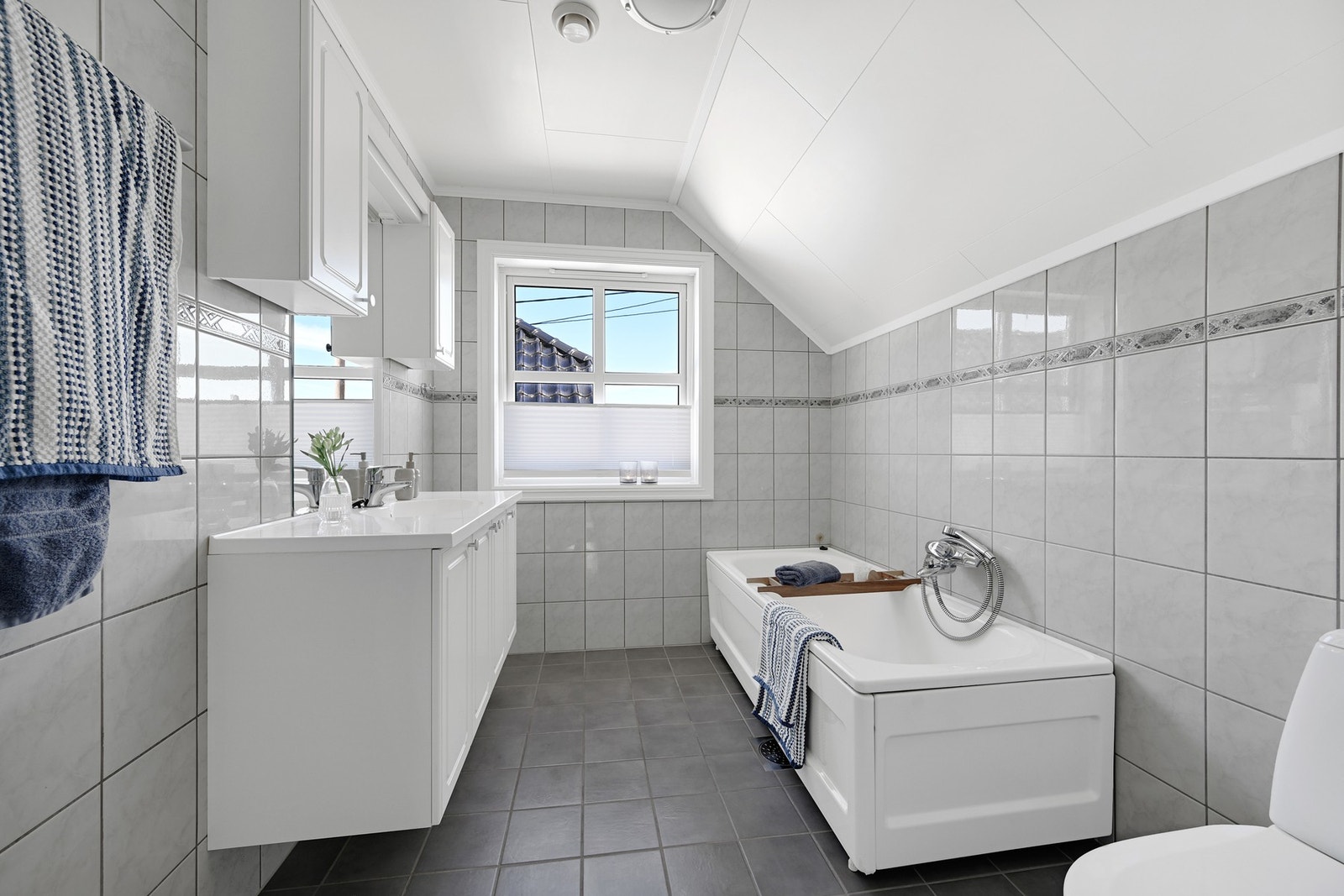 Badet i andre etasje er flislagt i lyse toner og har både badekar, servantinnredning og toalett. Galleribilde