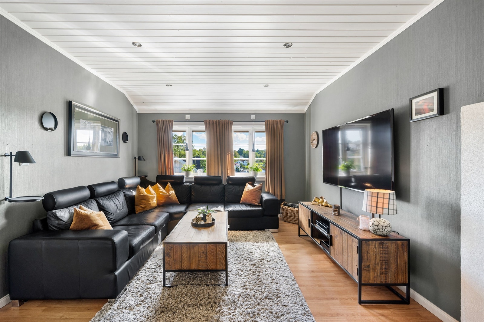 Loftstuen er innredet som en romslig TV-stue med downlights i taket og vinduer mot elva. Galleribilde