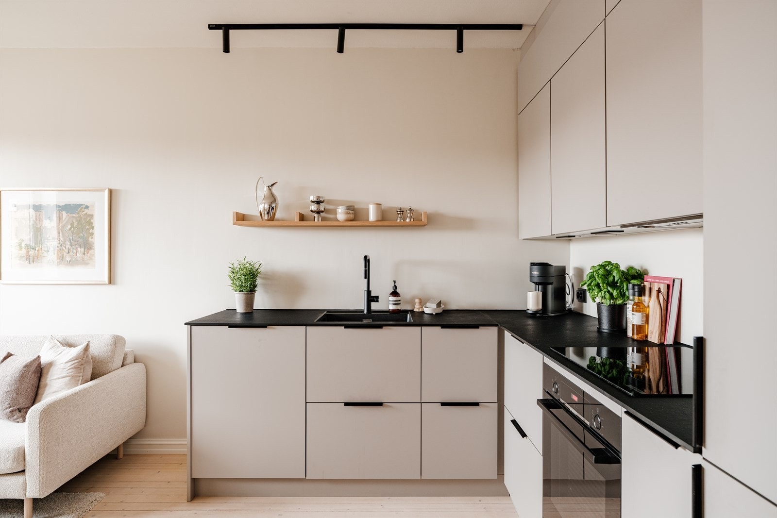 Det stilrene kjøkkenet har et moderne og tidløst uttrykk, med glatte, laminerte fronter og en elegant benkeplate i kompaktlaminat. Integrert belysning under overskapene gir godt arbeidslys og fremhever kjøkkenets rene linjer og gjennomførte materialvalg. Galleribilde