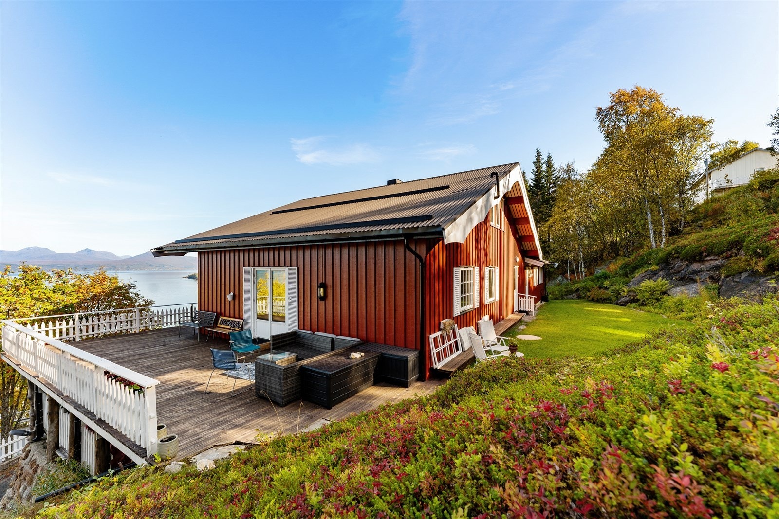 Skrånende og opparbeidet tomt med plen, grøntarealer og variert beplantning, kombinert med synlig fjell som fremhever tomtens naturskjønne preg. Galleribilde