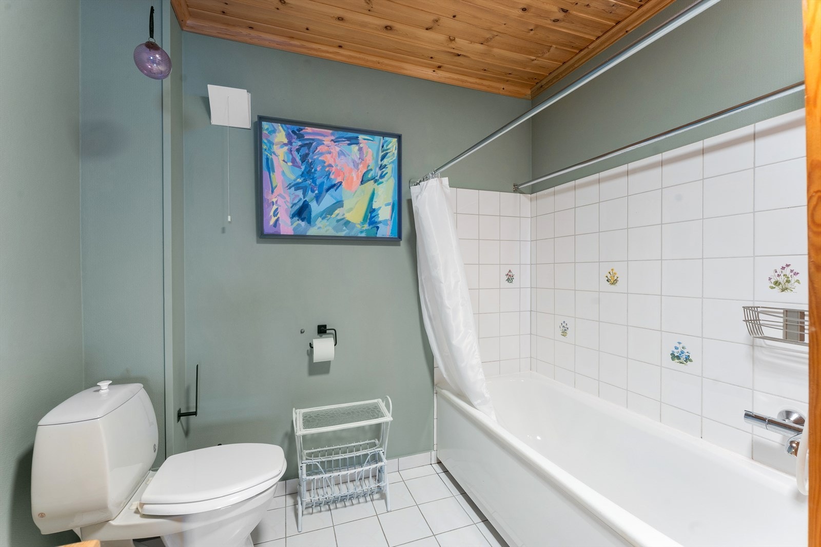 Badet er innredet med servant med underskap, høyskap, speil med belysning, badekar og gulvmontert toalett. Galleribilde