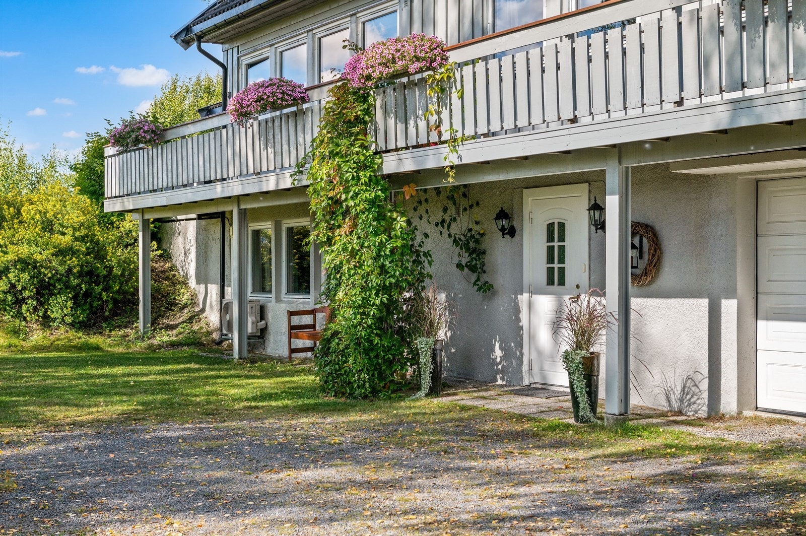 Inngangsparti på bakkeplan med trappefri adkomst fra gruset gårdsplass. Det er garasje i sokkel. Galleribilde