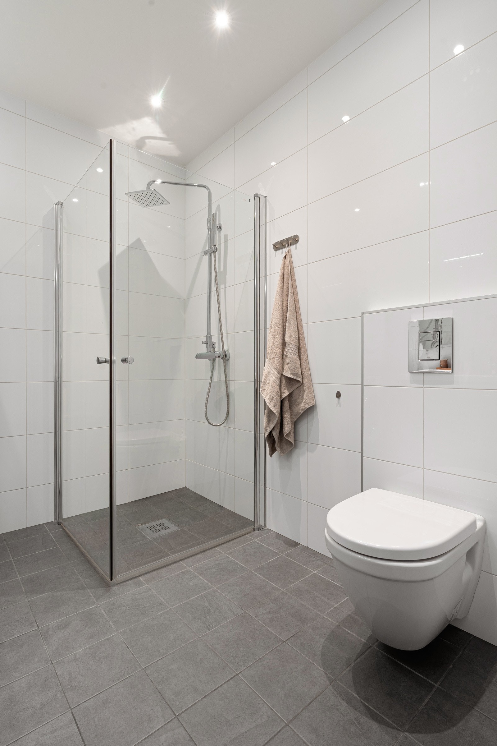 Badet er utstyrt med praktisk vegghengt wc, stort dusjhjørne og opplegg for vaskemaskin.