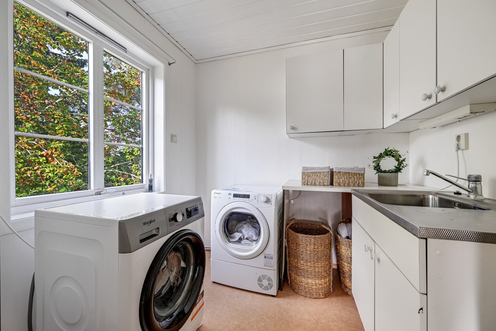 Praktisk vaskerom med skyllekum i stål, opplegg for vaskemaskin og rikelig med skapplass. Galleribilde