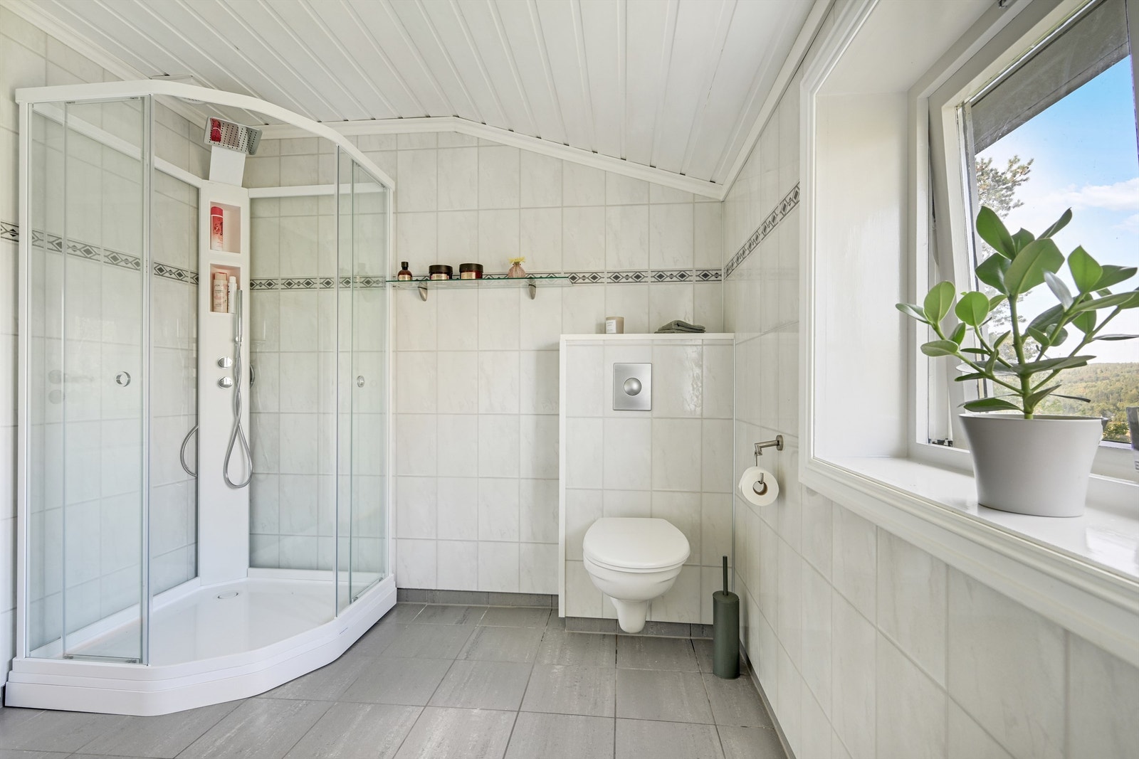 Badet har dusjkabinett og vegghengt toalett med innebygd sisterne. Galleribilde