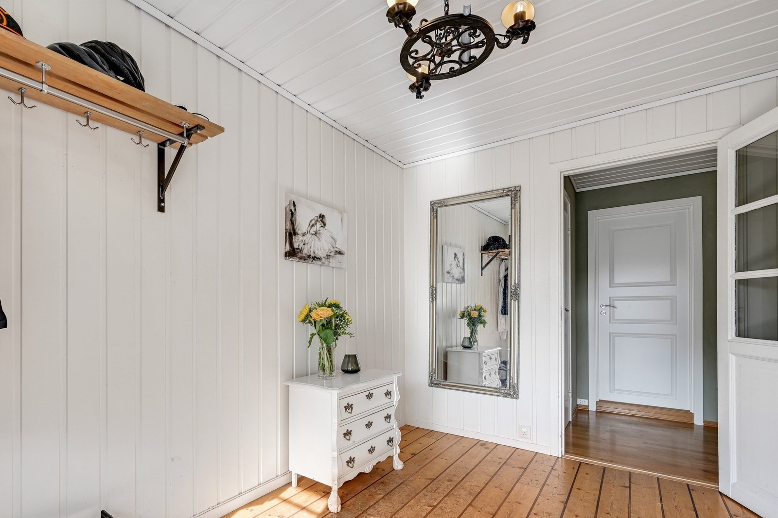 En romslig og hyggelig entré med tregulv og panelte vegger. Galleribilde