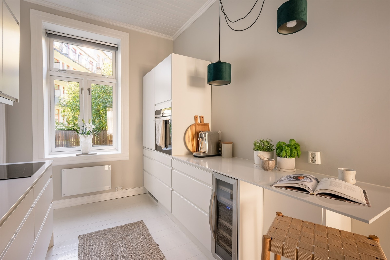 Kjøkkeninnredning fra Designia med hvite, glatte fronter, benkeplate av komposittstein og nedfelt kjøkkenvask med armatur Galleribilde