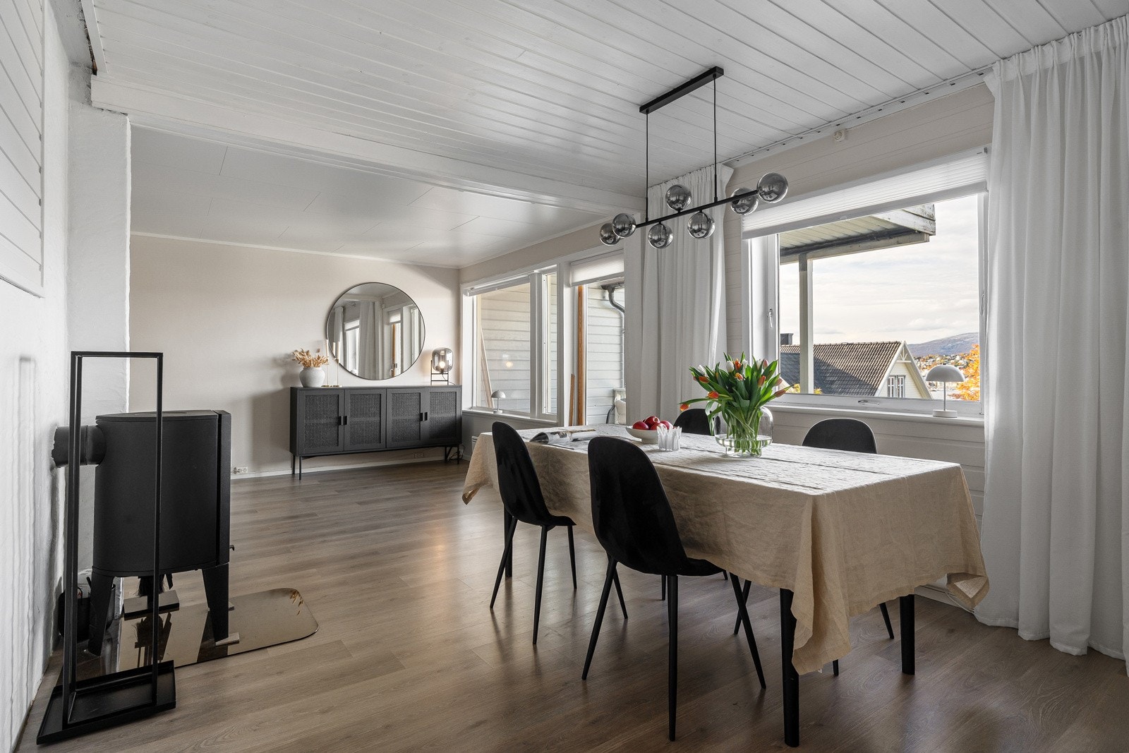 En sosial og praktisk løsning der kjøkken, spiseplass og stue ligger fint i sammenheng. Vedovnen tilfører varme og en lun atmosfære rundt spiseplassen