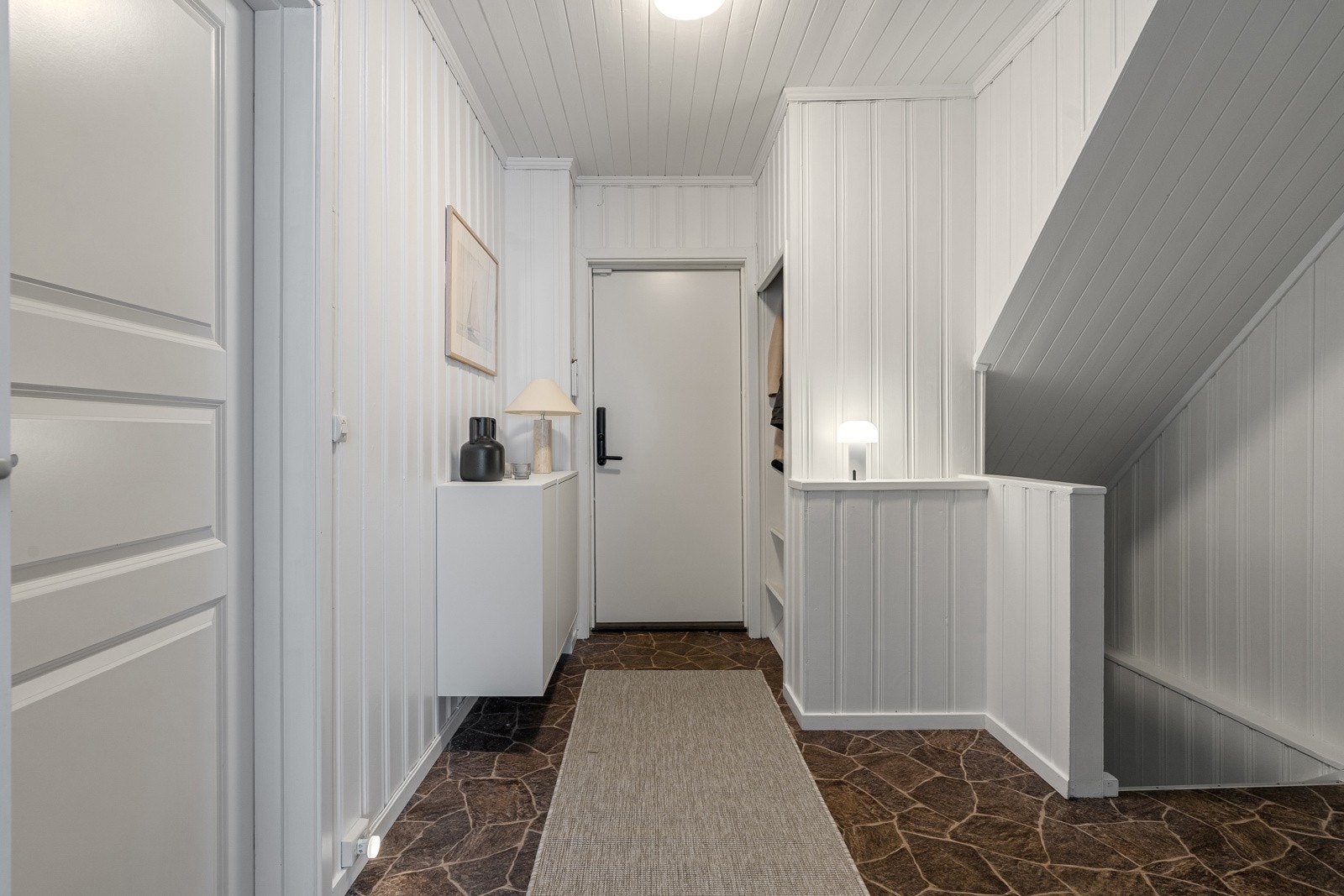 Trappen leder videre ned til en innholdsrik og praktisk underetasje.