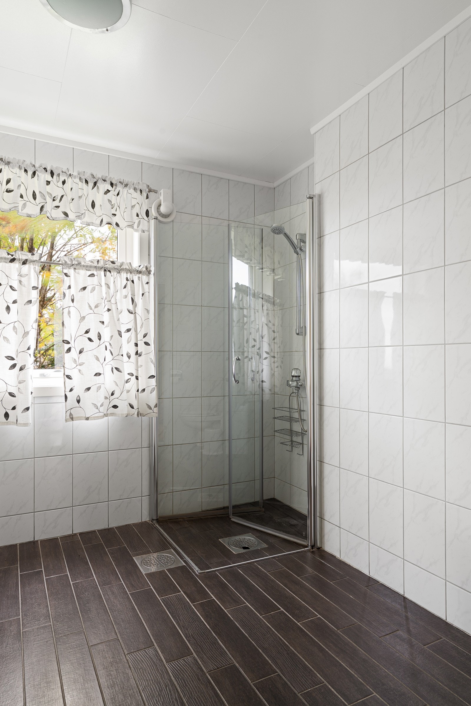 Badet er innredet med servant, veggmontert toalett og dusjhjørne.
