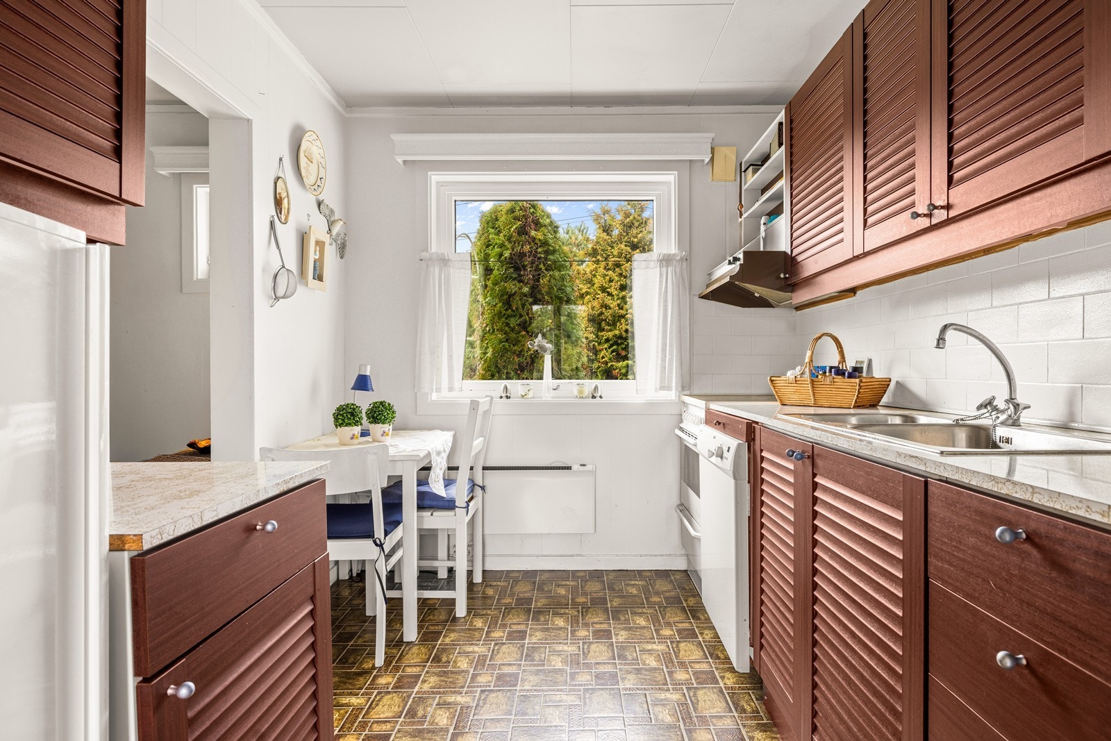 Kjøkkenet har spiseplass ved vinduet og vegger kledd med malte panelplater. Galleribilde