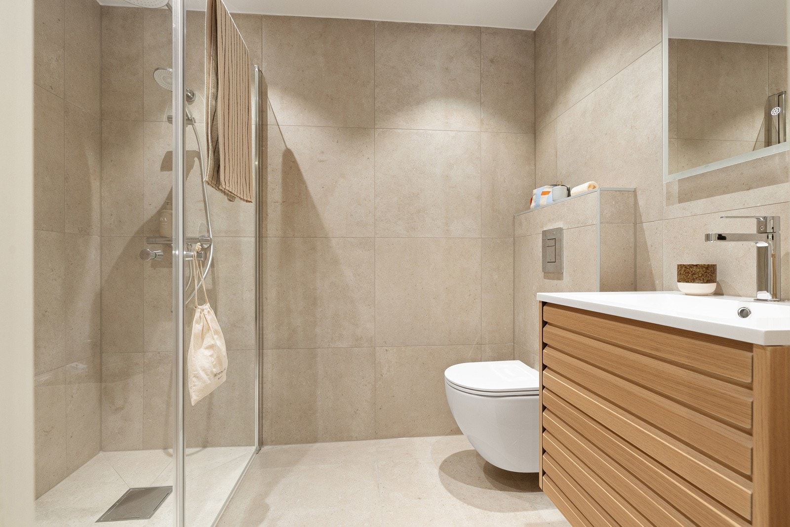 Badet har lyse 60 x 60 cm flis på gulv og vegger. Malte plater med downlights i himling. Elektrisk gulvvarme Galleribilde