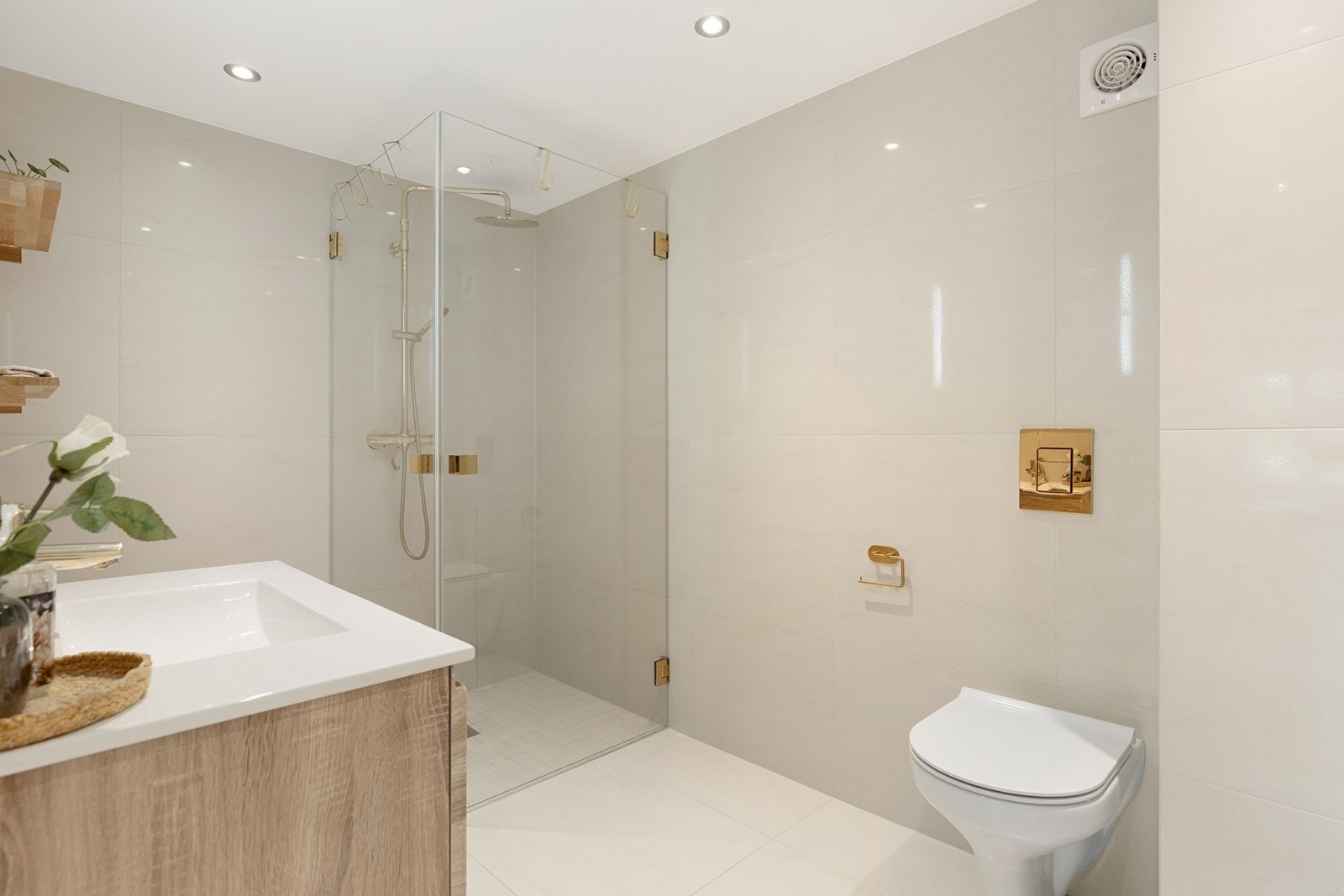 Badet i 1. etg. er lekkert utstyrt med moderne dusjkabinett, vegghengt toalett. og skuffinnredning med gulldetaljer. Galleribilde