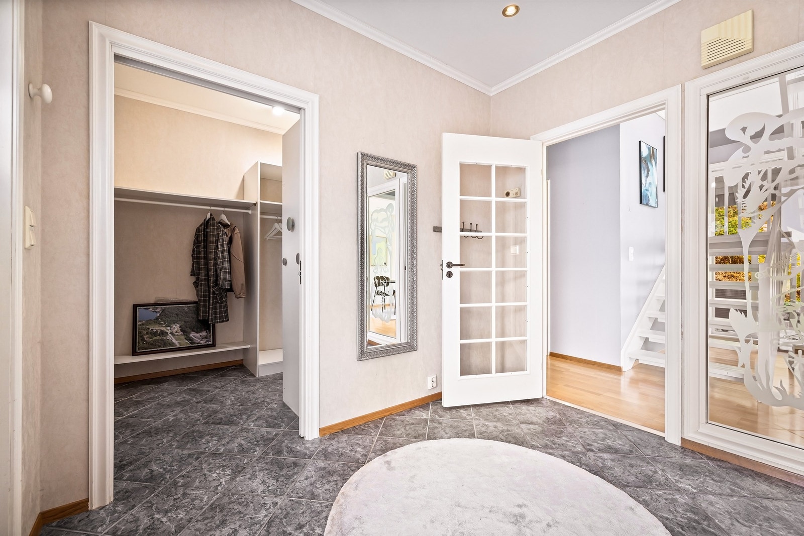 En hyggelig entré som leder til gang med trapp til 2. etasje. Dekorasjon på vindu til gang finner man igjen i vindu på ytterdør. Galleribilde