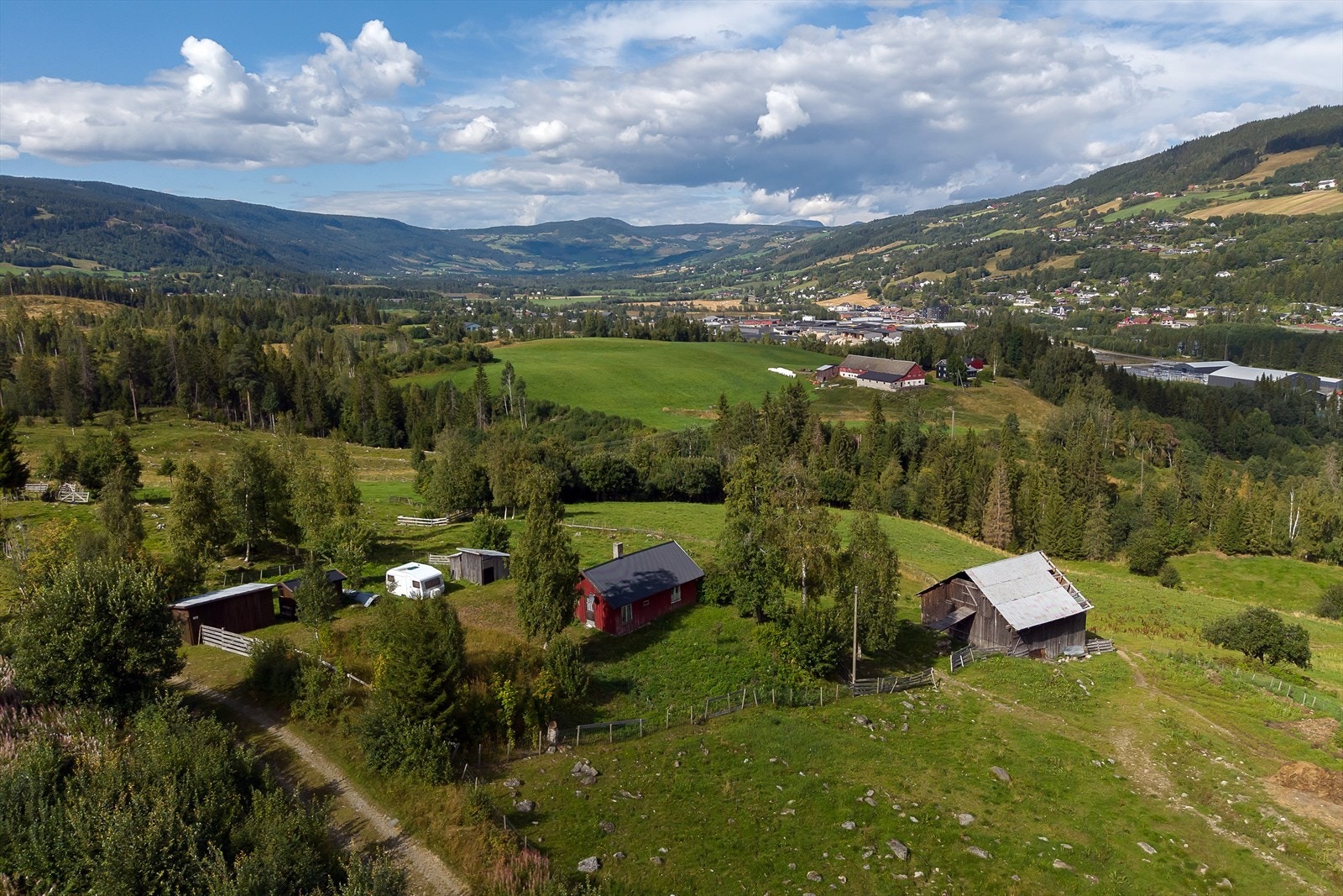 Småbruk med våningshus og fire tilhørende bygninger, beliggende i et vakkert kulturlandskap. Galleribilde