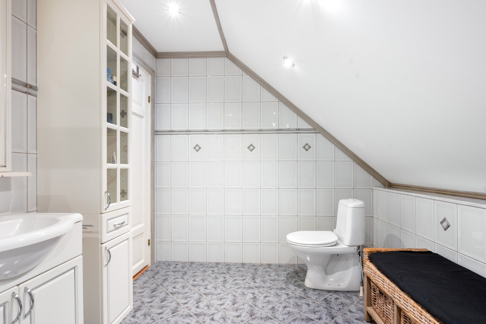 Badet består av gulvmontert toalett, dusjkabinett, servantseksjon med skuffer og skap. Galleribilde