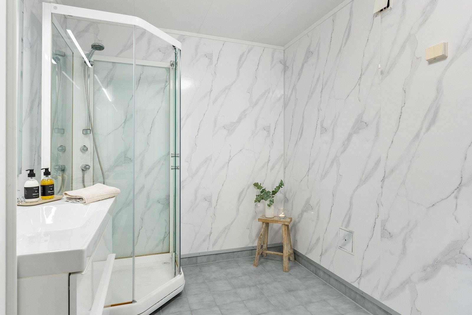 Bad i første etasje med dusjkabinett og baderomsplater på veggene. Badet er av eldre dato og har behov for oppgradering for å oppnå dagens krav til standard. Galleribilde