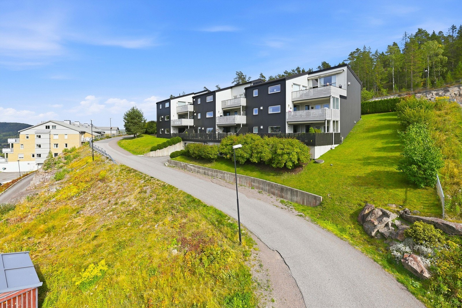 Sameiet har en pent opparbeidet skrånende tomt med plen og beplantninger og praktiske støttemurer Galleribilde
