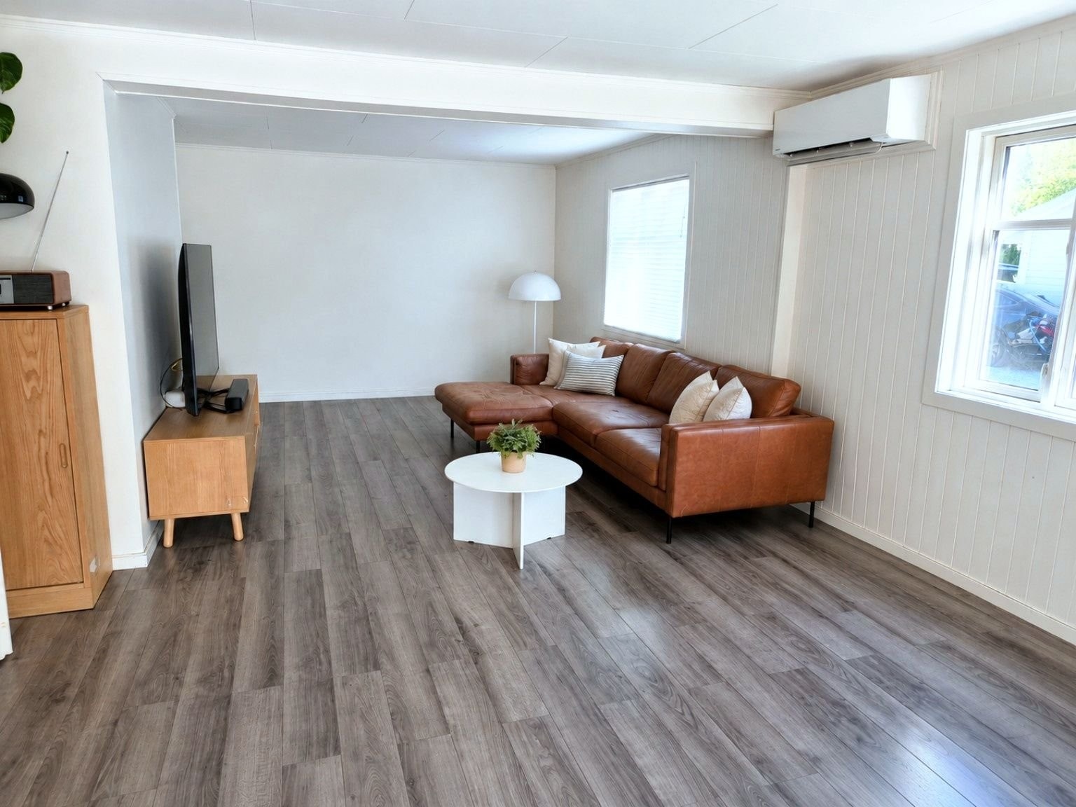 En lun del av stuen med god plass til TV- og sofagruppe. Bildet er KI-redigert ved at en barnegrind er fjernet – rommet er ellers uendret. Galleribilde