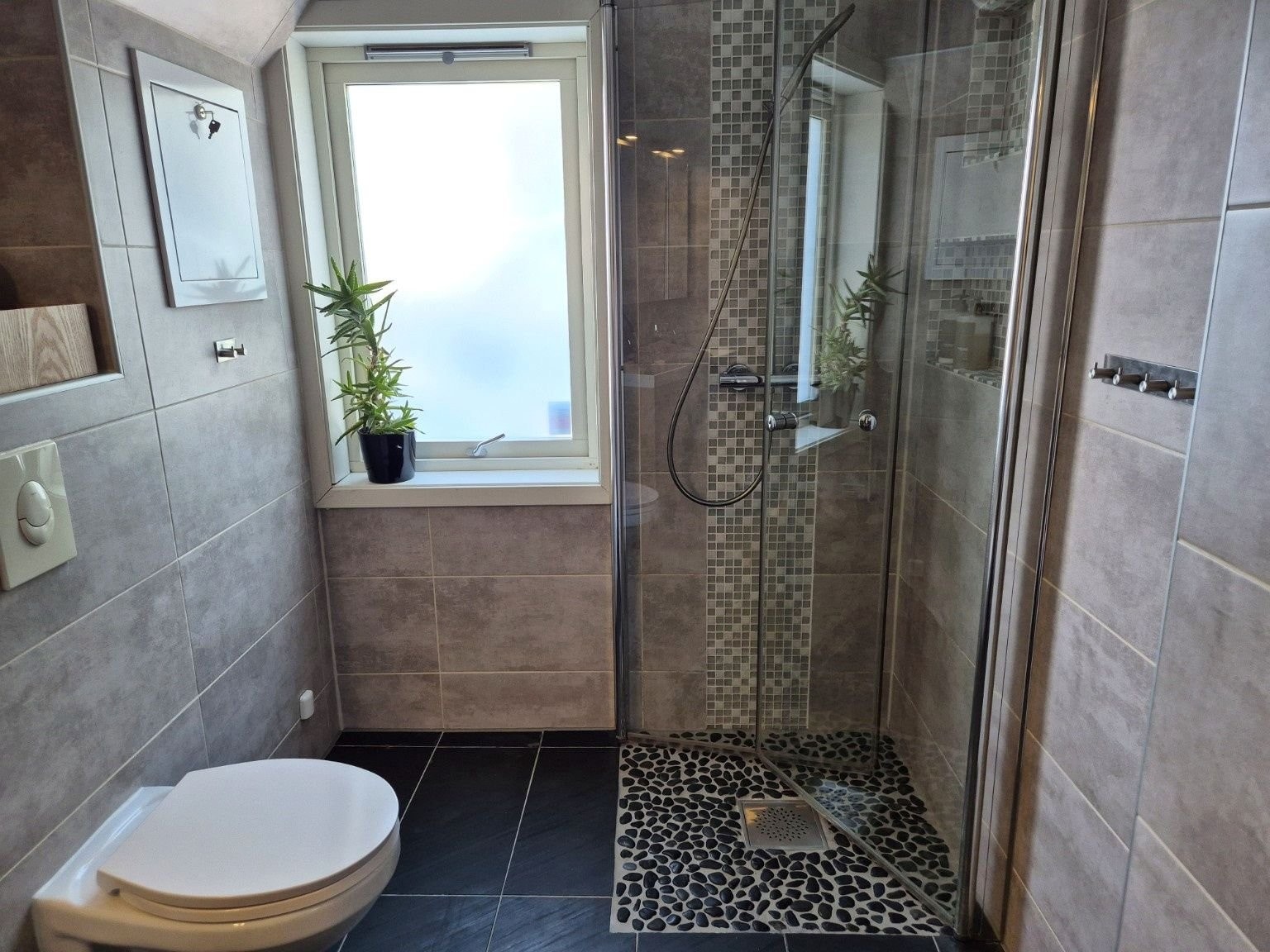 Bad i 1. etasje med dusj og vegghengt toalett. Badet ble totalrenovert i 2014, og dokumentasjon foreligger i Boligmappa. Galleribilde