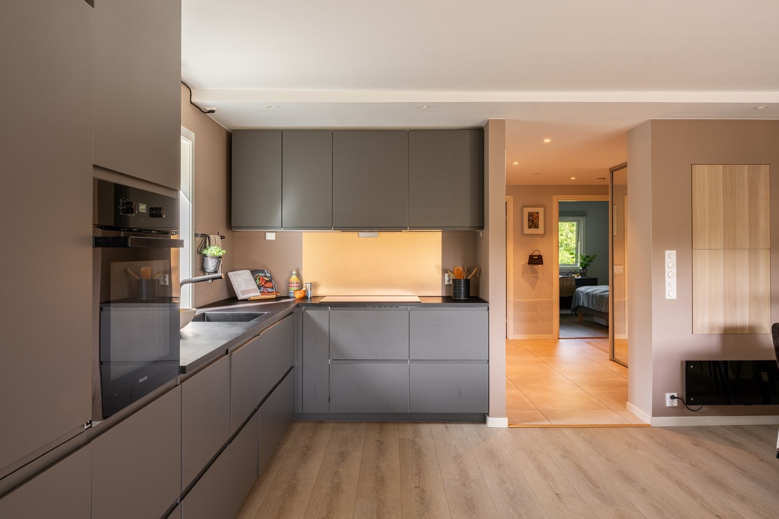 Over kokesonen er det lagt metallplater som backsplash, mens vindu, takspotter og downlights gir en lys og trivelig arbeidssone. Kjøkkenet er utstyrt med induksjonstopp, stekeovn, oppvaskmaskin, kjøleskap, fryser og en kullfilterventilator. Galleribilde
