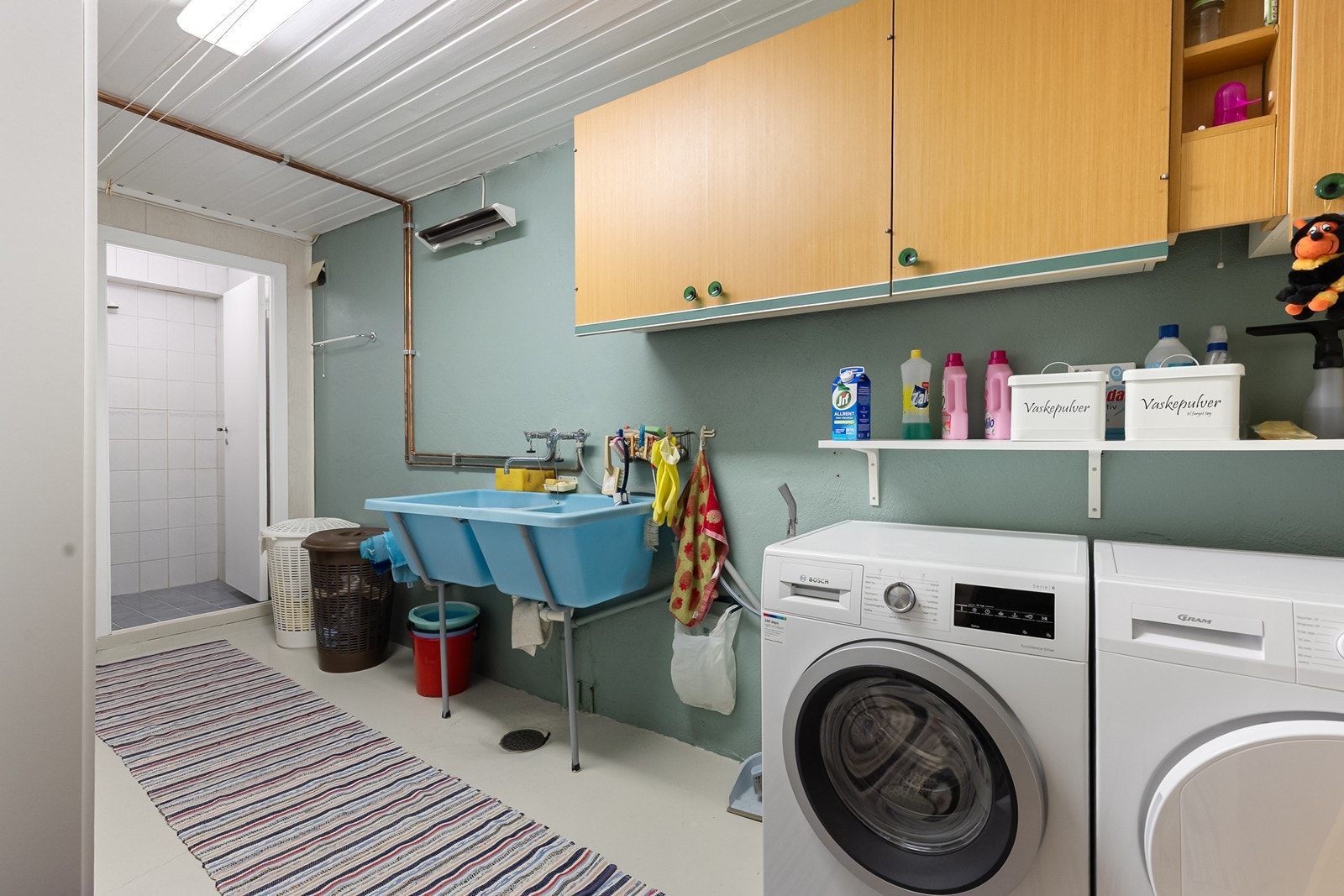 Praktisk vaskerom med god skapplass, utslagsvask og opplegg for vaskemaskin og tørketrommel. Galleribilde