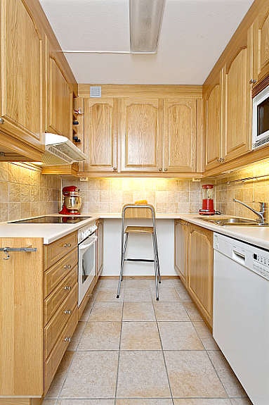 Kjøkkeninnredning fra 2003 i profilert eik. Fliser på gulv og over benk. Galleribilde