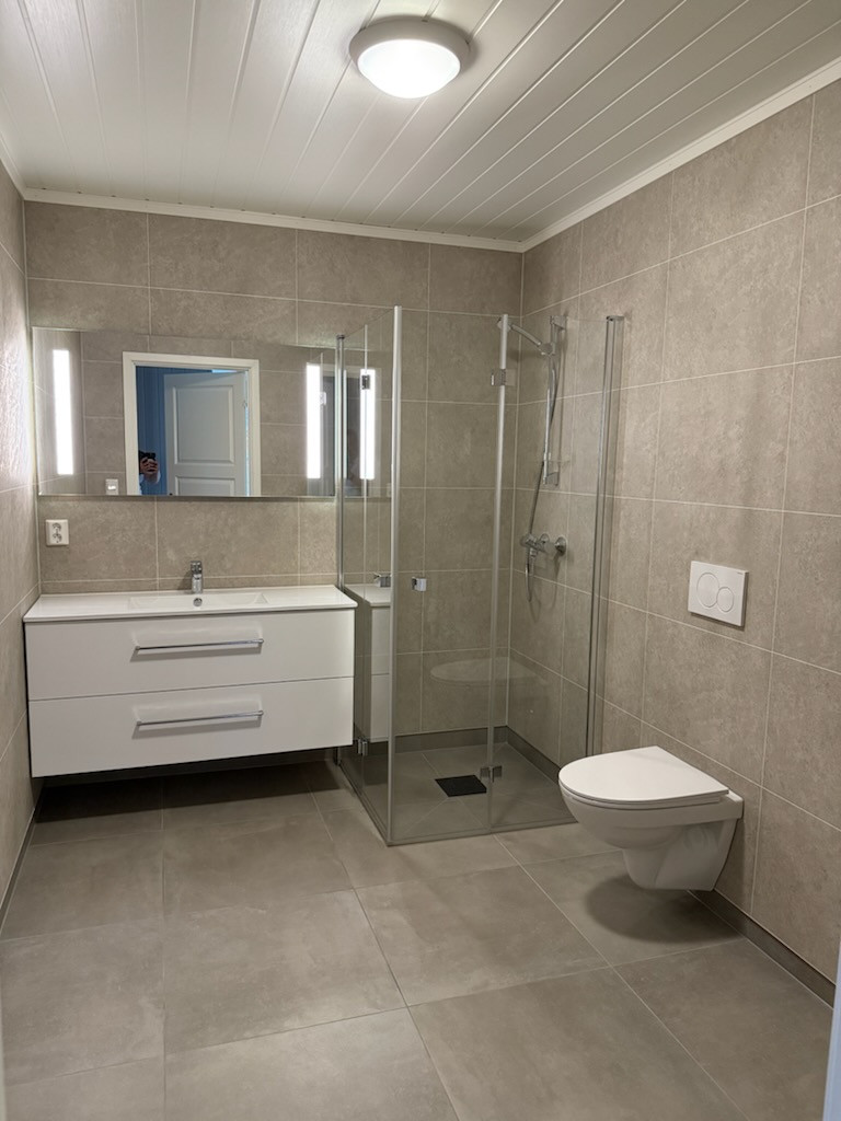 Badet kommer med keramiske fliser som standard og baderomsplater på vegg. Kjøper står fritt til å velge innhold, omfang og standard på badet. Bildet er en illustrasjon og kan fravike fra endelig leveranse