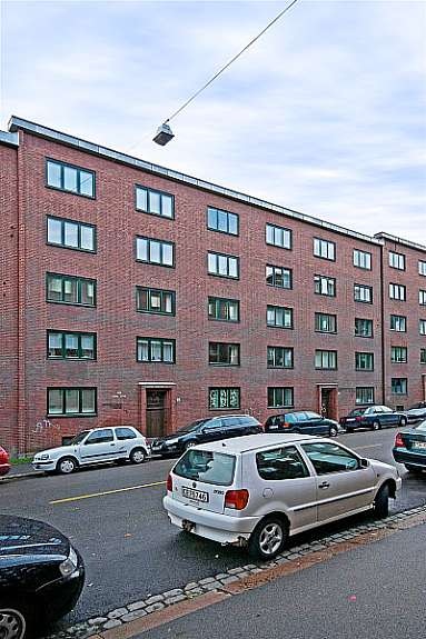 Stor bakgård med lekeplass, sittegrupper, trær og prydbusker. Galleribilde