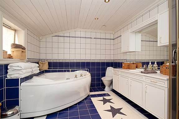 Stort flislagt bad med varmekabler, toalett, dusjkabinett, hjørnebadekar og servant/baderomsmøbel med god skapplass. Galleribilde