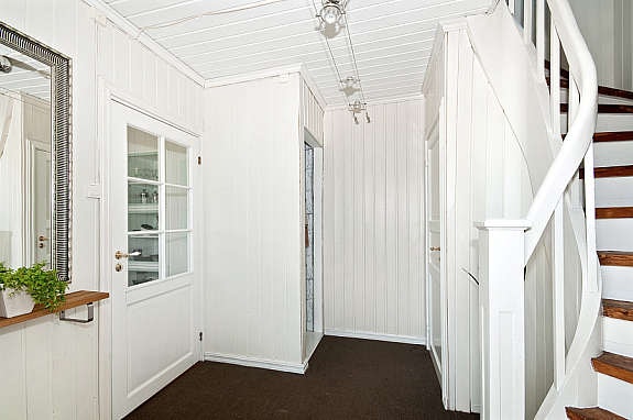 Entrè med sisalteppe på gulv , malt panel på vegger og malt panel i tak. Her er et lite innebygd skap. Trapp opp til 2 etasje og trappenedgang til kjeller. Galleribilde