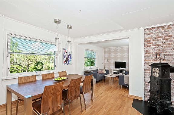 Spisestue med parkett på gulv, mat tapetpå vegger og plater i tak. Her er en eldre vedovn. Galleribilde