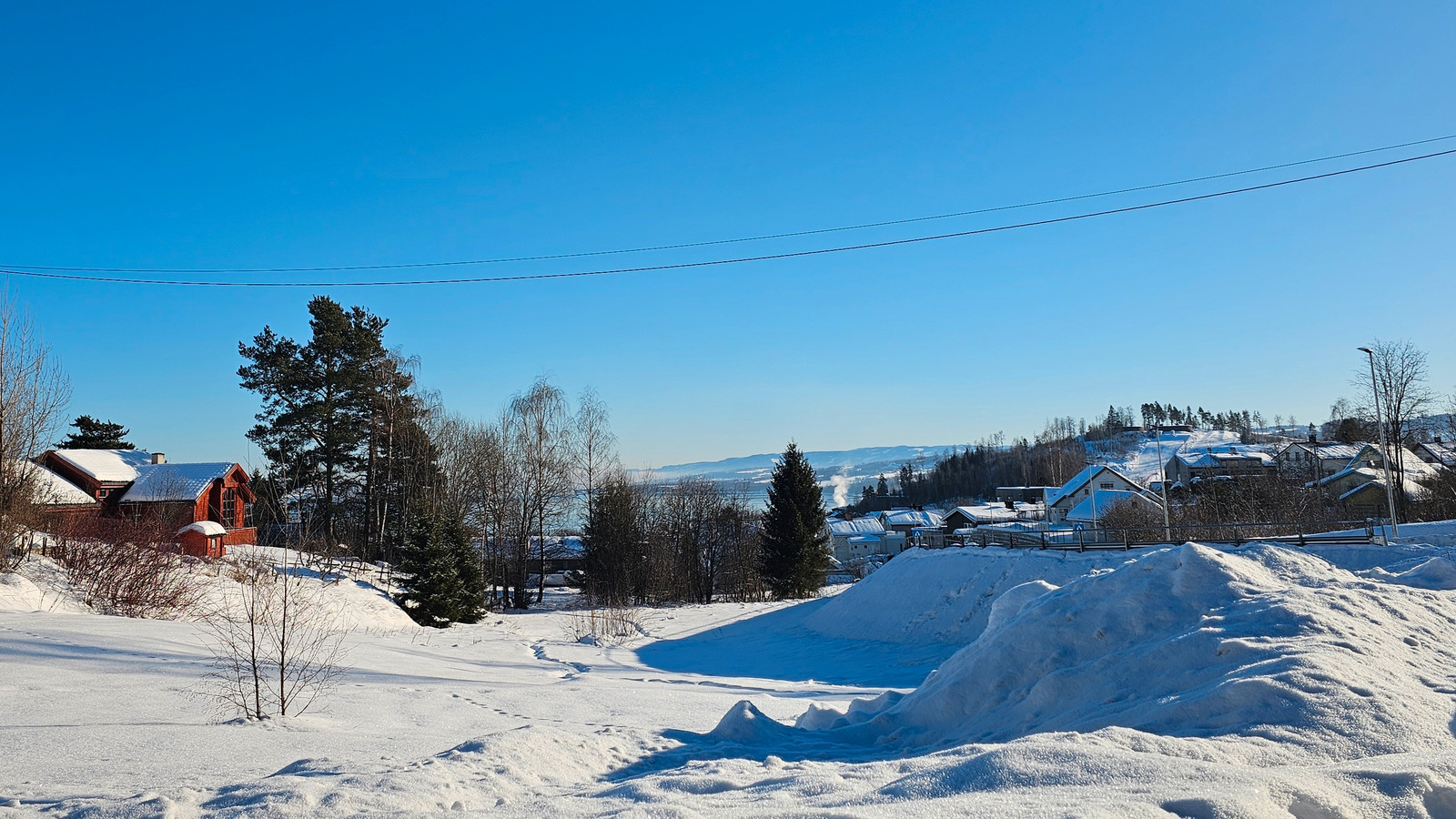 Utsikt mot parken rett inntil  samt Hovdetoppen og Mjøsa med Totenåsen i bakgrunnen.