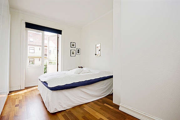 Stort og lyst soverom med parkett på gulv, malt strie på vegger og takessplater i himling. God skapplass og utgang til brannbalkong Galleribilde